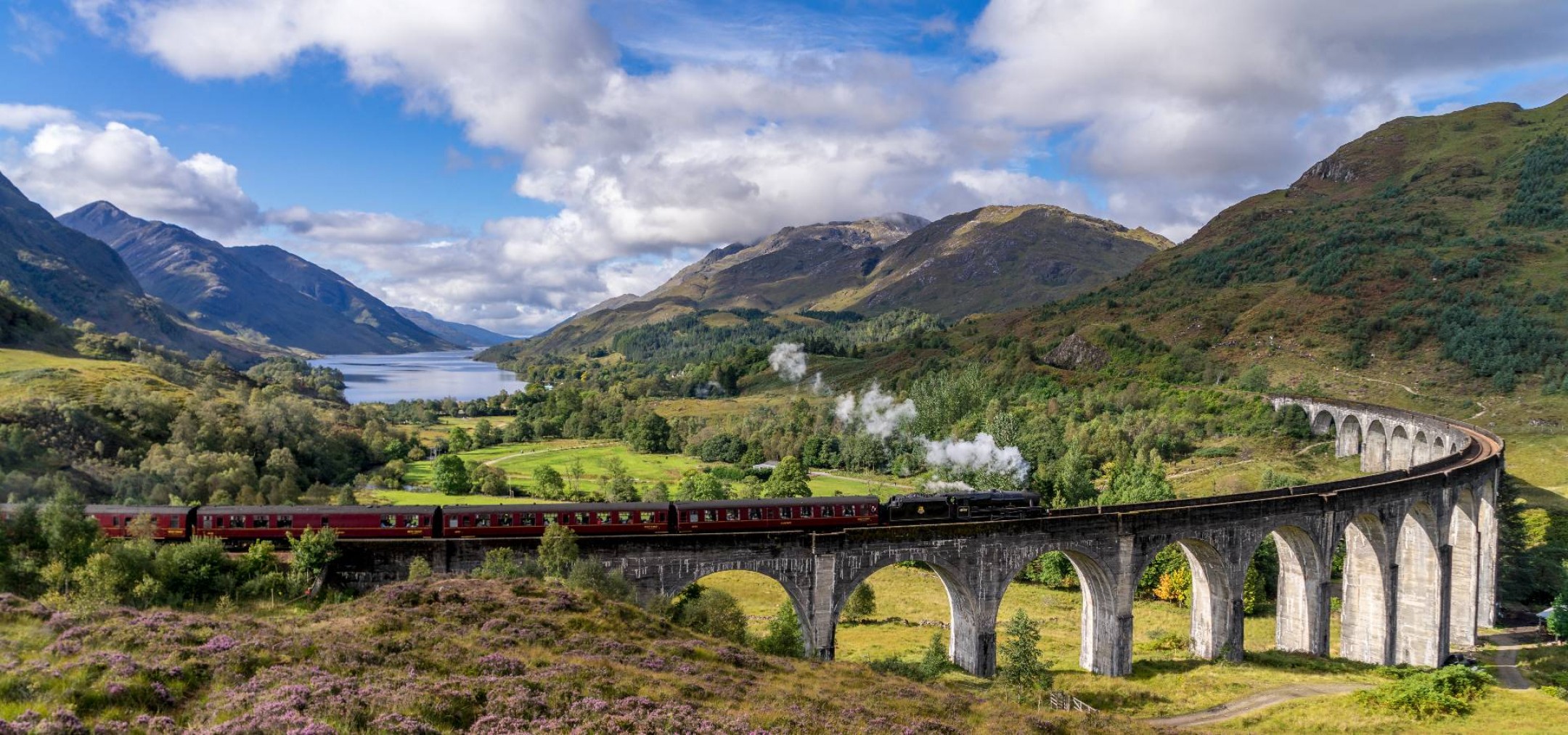 jacobite steam train crossing glenfinnan viaduct in scotland