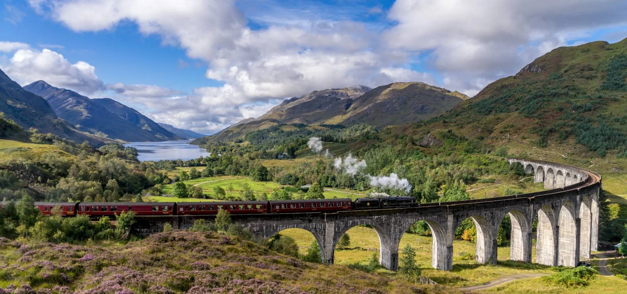jacobite steam train crossing glenfinnan viaduct in scotland