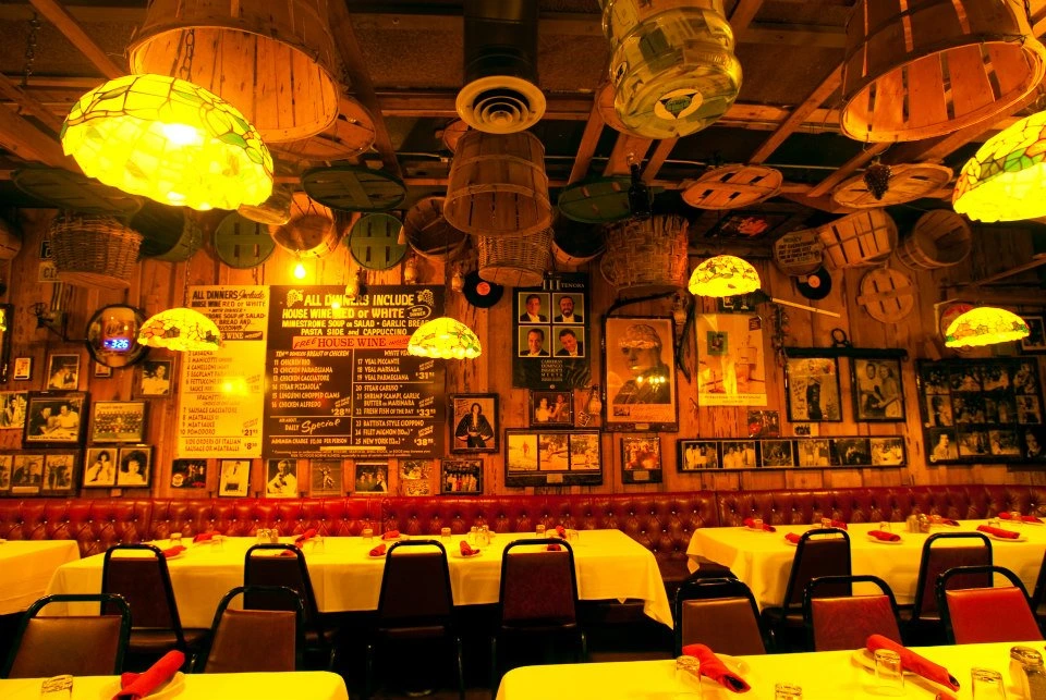 a dimly lit dining room with photos and curios on the wall at battista's hole in the wall italian restaurant off the strip in las vegas