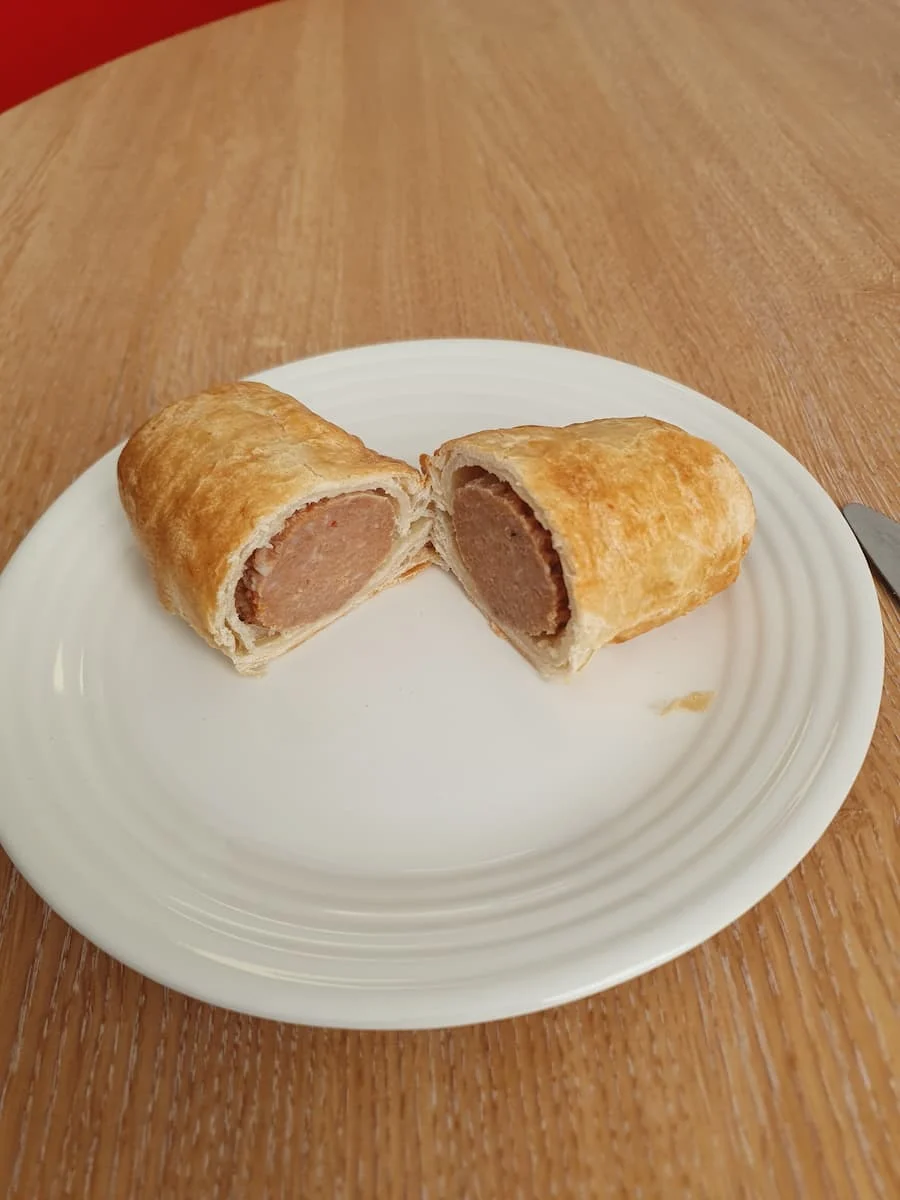 a sweet chili sausage roll sliced in half on a white plate