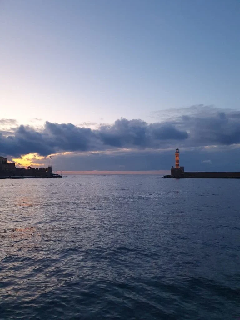 a lighthouse and harbor wall at twilight in chania crete greece