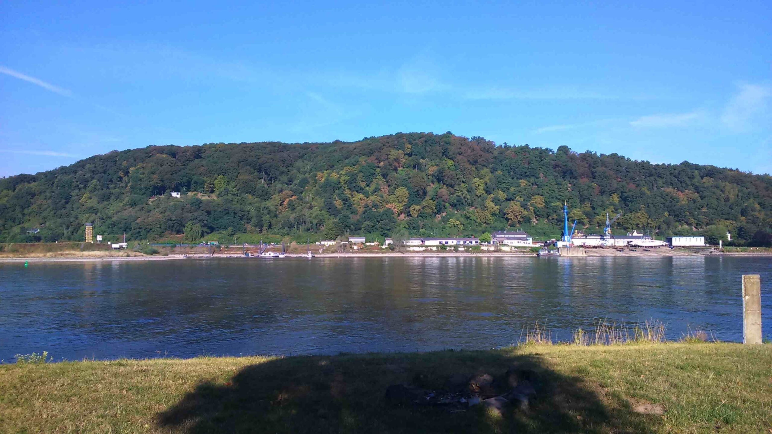 Rhein river seen with a green hill on the background, on a sunny day.