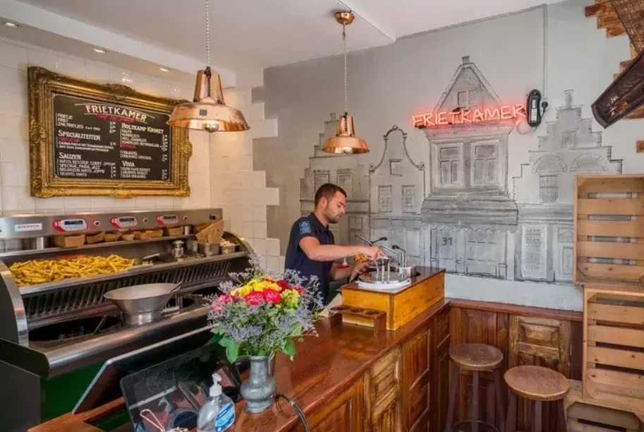 A person making frietjes at a friet shop.