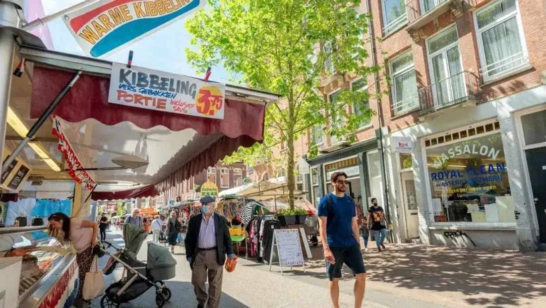 People walking on a Dutch street past a kibbeling stall.