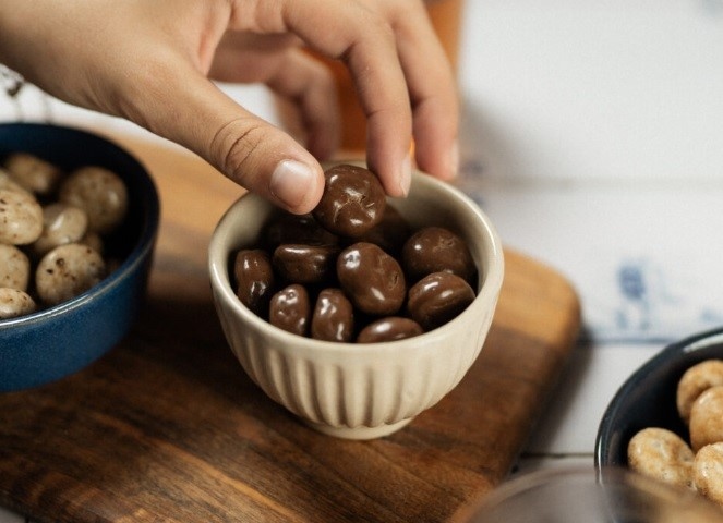 Pepernoten in a cup with a hand reaching for them