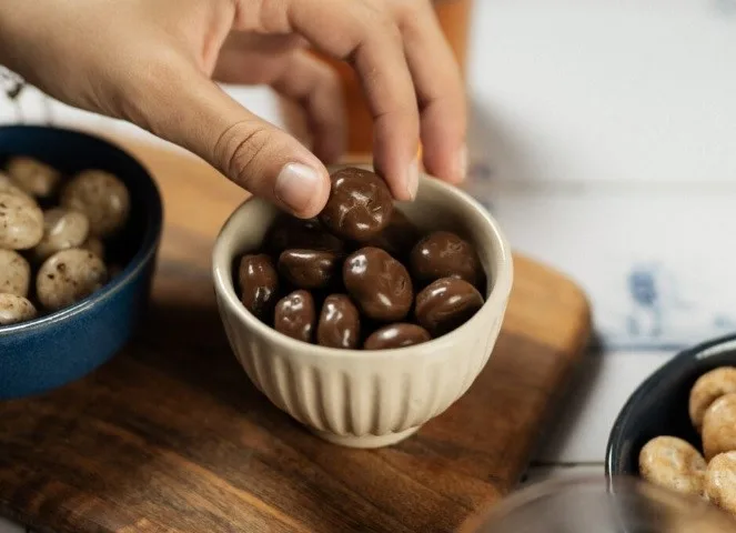 Pepernoten in a cup with a hand reaching for them