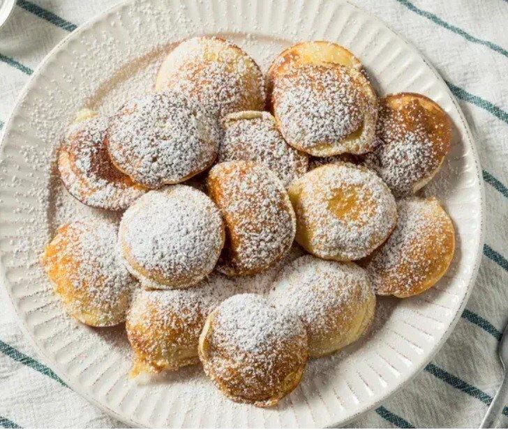 Poffertjes on a plate covered in powder sugar