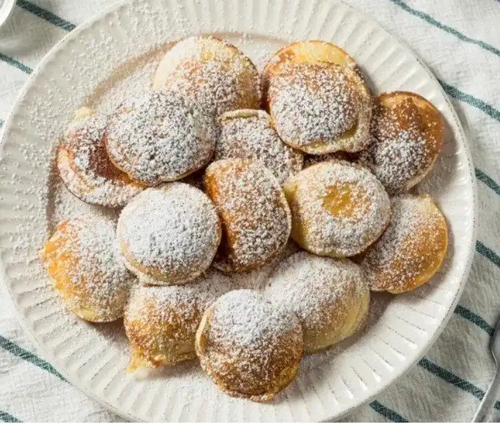 Poffertjes on a plate covered in powder sugar