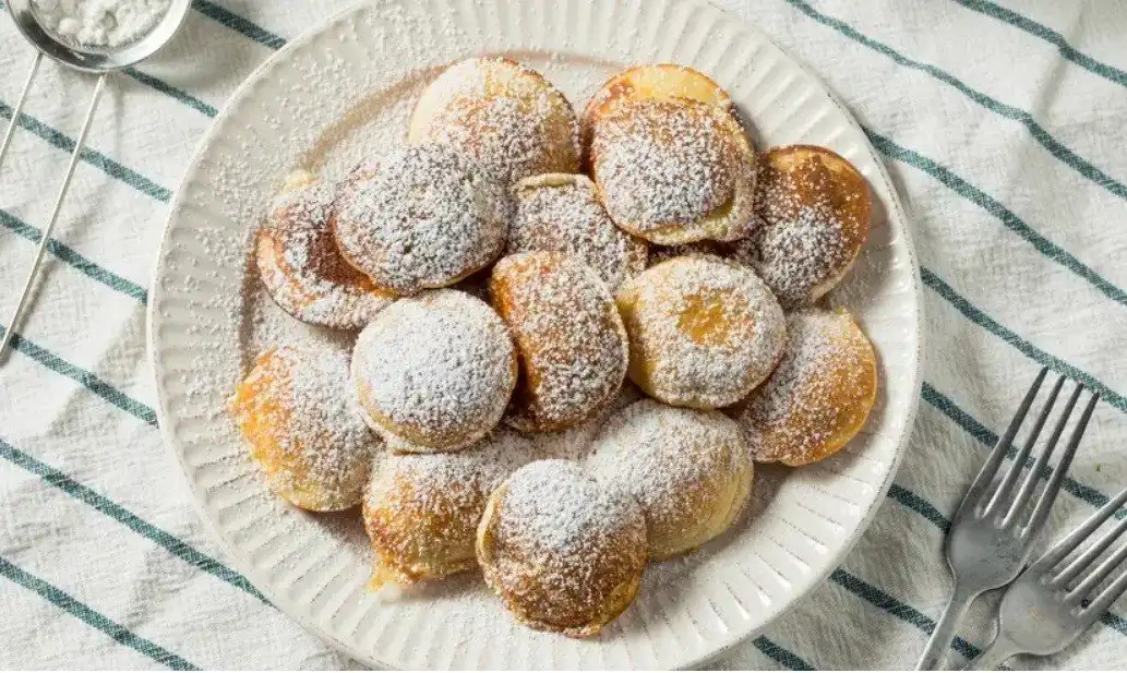 Poffertjes on a plate covered in powder sugar