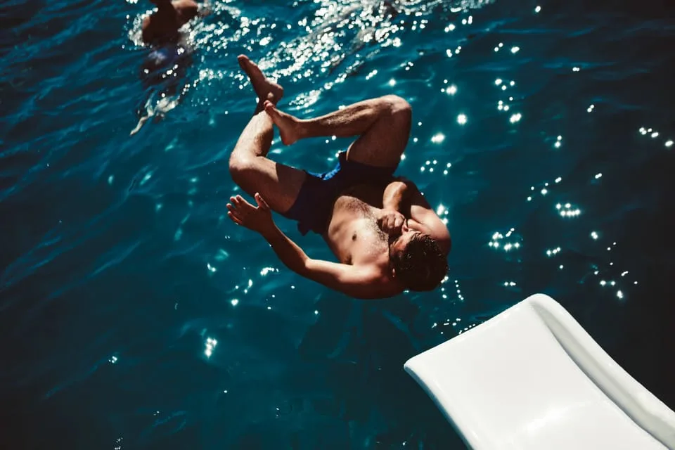 a man in swimming shorts dives off a super yacht into the mediterranean off ibiza spain