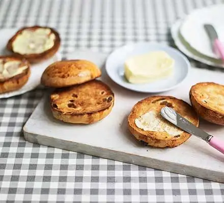 toasted teacakes are a british snack filled with fruit and served with butter and jam