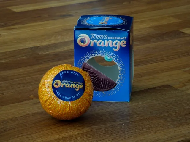 a terry's chocolate orange in an orange foil wrapper next to a blue box