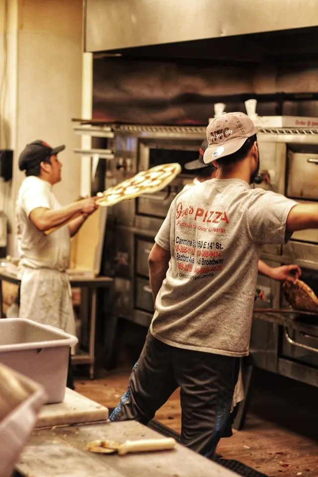 a pizzaiolo puts a new york style pizza in a pizza oven at joe's pizza in greenwich village new york usa