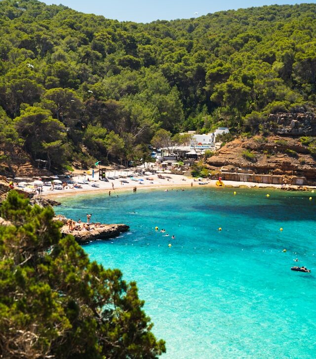 blue mediterranean sea and a white sandy beach with sunbeds and parasols in ibiza balearic islands spain