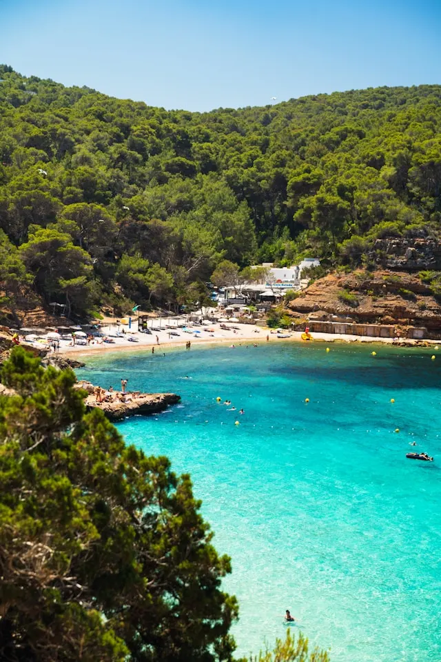 blue mediterranean sea and a white sandy beach with sunbeds and parasols in ibiza balearic islands spain