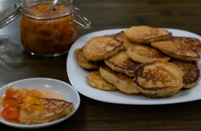 a plate of machkatebi georgian panckaes on a white plate with a jar of homemade apricot jam in the background