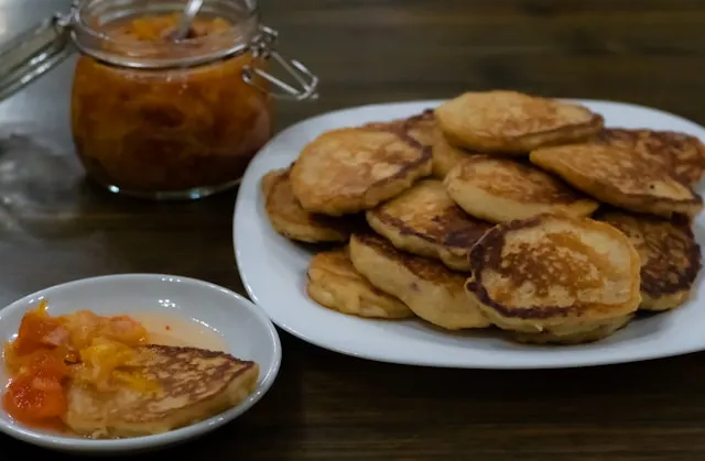 a plate of machkatebi georgian panckaes on a white plate with a jar of homemade apricot jam in the background