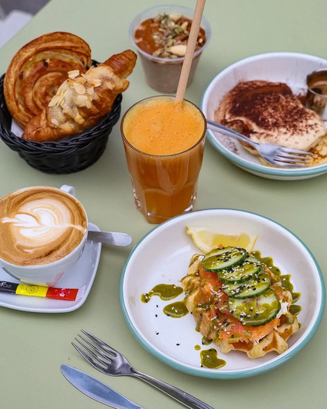 A selection of dishes including waffles with salmon, pastries, freshly squeezed juice and coffee