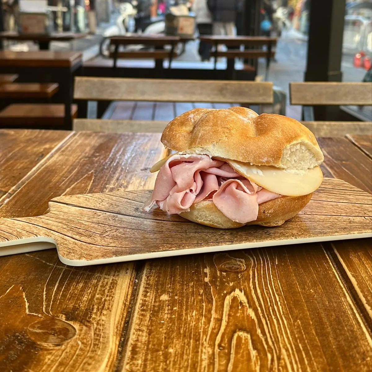 a mortadella sandwich on a wooden chopping board from murtadela sandwich shop in bologna italy