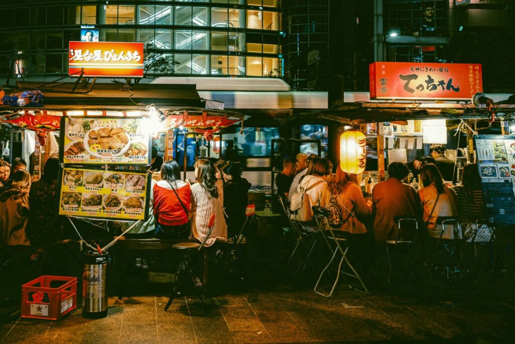 A group of people sitting at a yatai streetfood stalls in Fukuoka