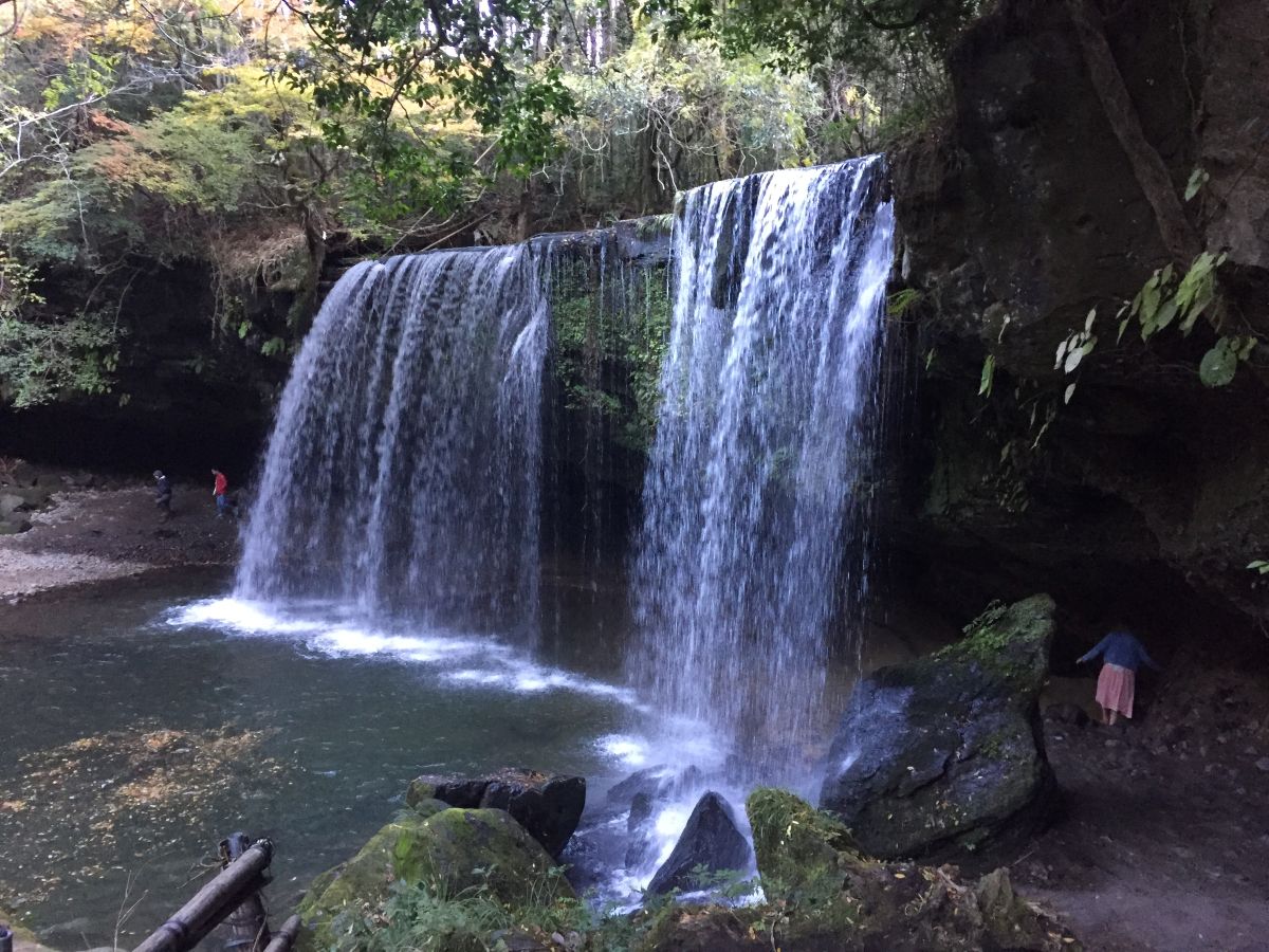 Woman walking behind Nabegataki Falls in Kyushu, Japan