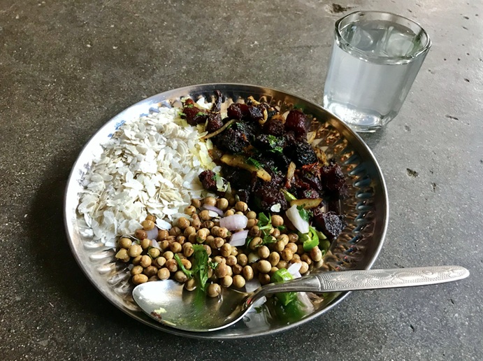 A plate of Nepalese food alongside a glass of Raksi 