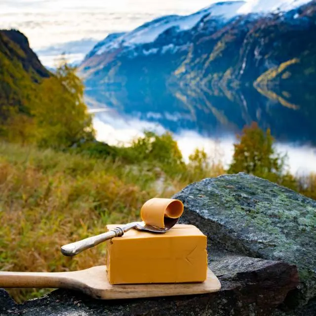 norwegian hard brown cheese brunost in front of a fjord in norway