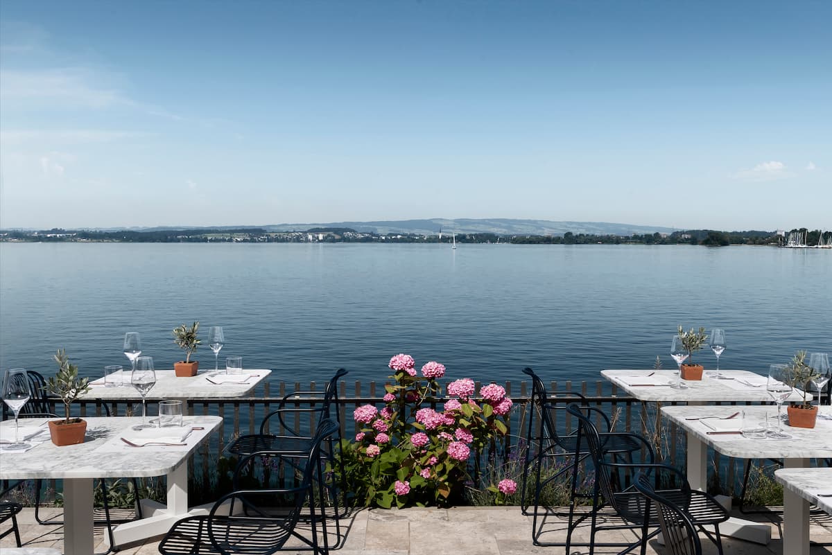 tables with seats and wine glasses overlooking zugersee lake from zur table restaurant in zug switzerland