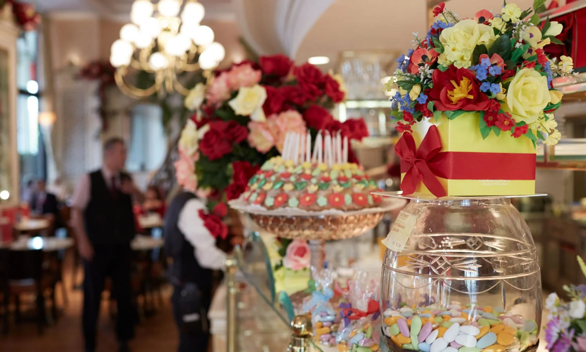a bouquet of flowers sits behind a colorful cake at cafe felix zurich switzerland