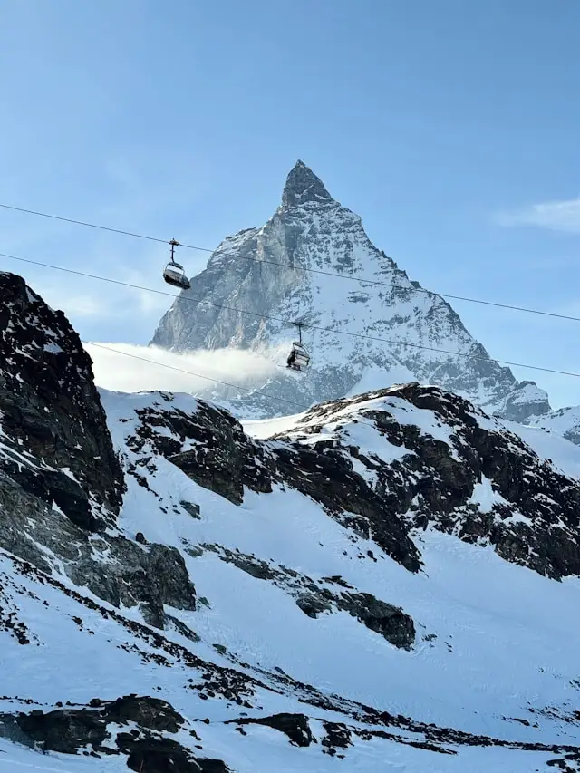 a ski lift on a mountain in a snow covered ski resort with the matterhorn in the background in the swiss alps