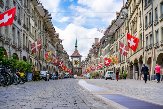 swiss flags on buildings on a steet leading to a gothic cathedral in bern switzerland