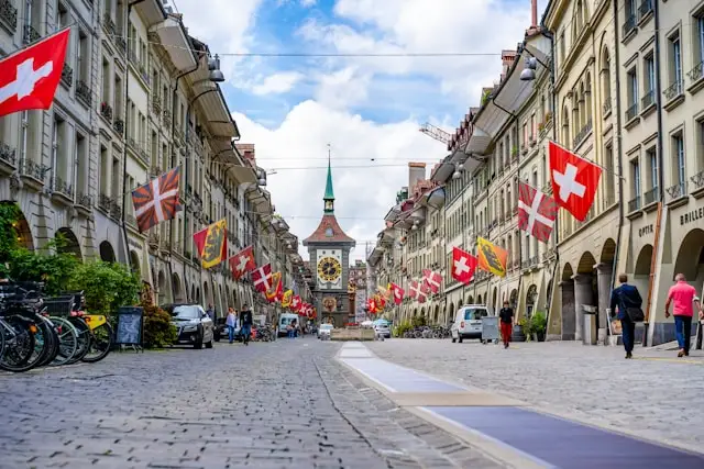 swiss flags on buildings on a steet leading to a gothic cathedral in bern switzerland
