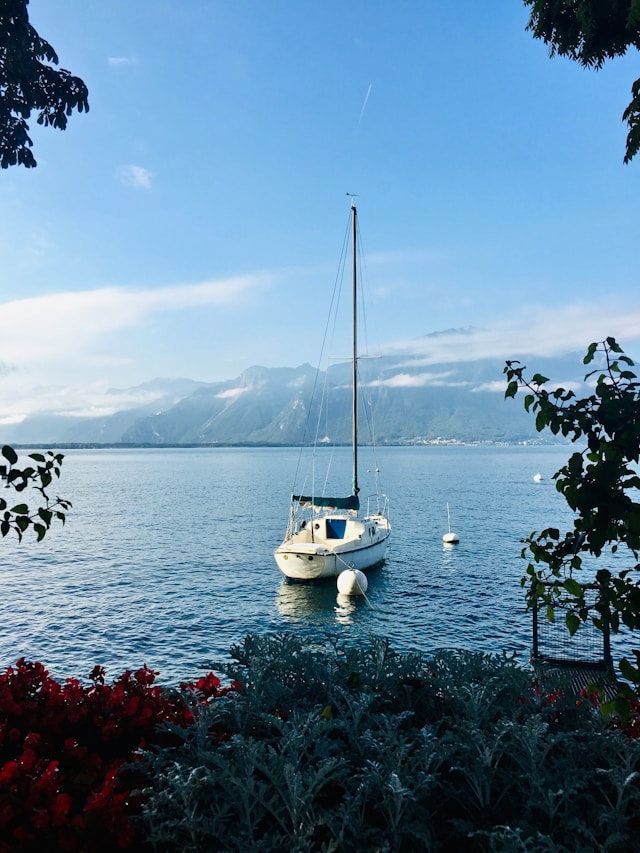 a sailboat on lake geneva switzerland with snowy alpine mountains in the background
