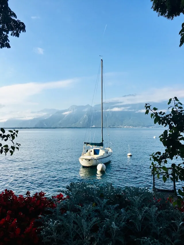 a sailboat on lake geneva switzerland with snowy alpine mountains in the background