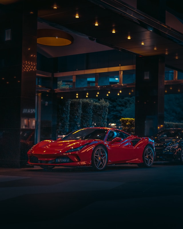 a red ferrari in twilight parked outside a building