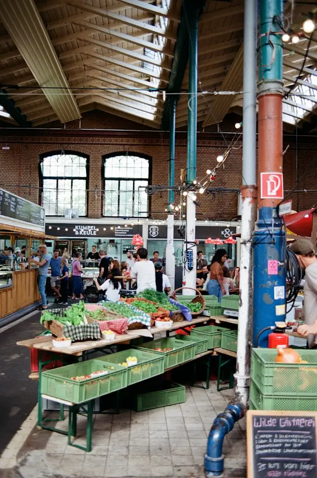 a historic building filled with food stalls and market traders at markthalle neun in berlin germany