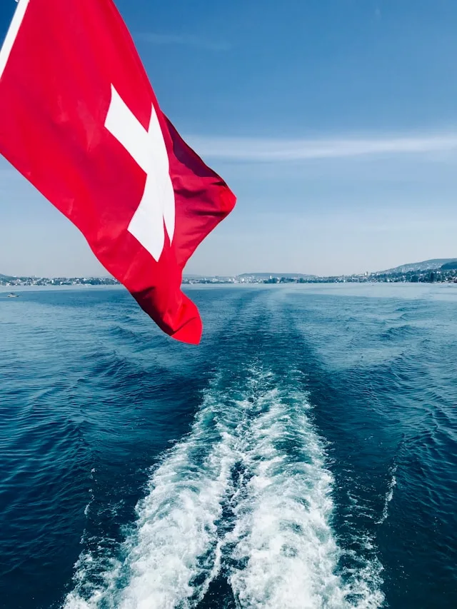 a boat flying the swiss flag in lake zurich switzerland