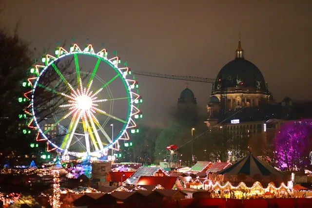 a ferris wheel and market stalls at night with the reichstag in the background at berlin christmas market germany