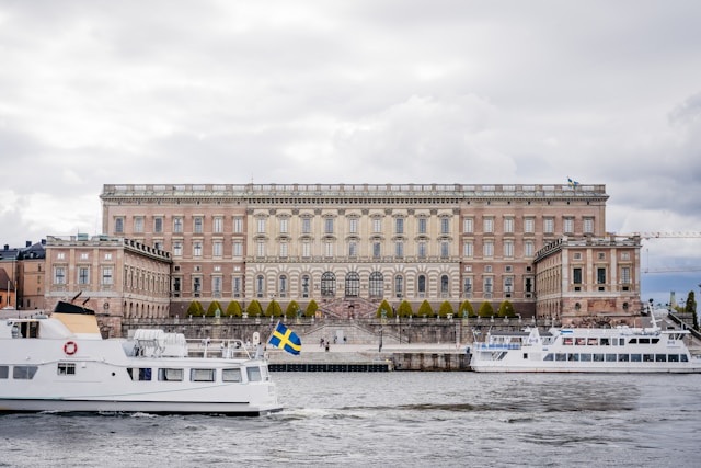 the royal palace backs on to the water where boats pass in gamla stan stockholm sweden