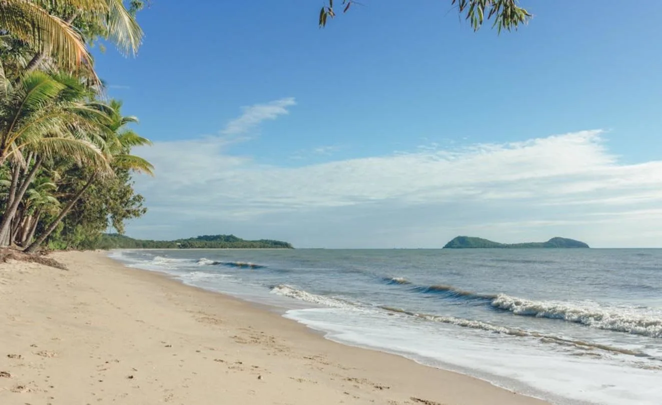 White sandy beach next to the sea with islands in the background, on a sunny day