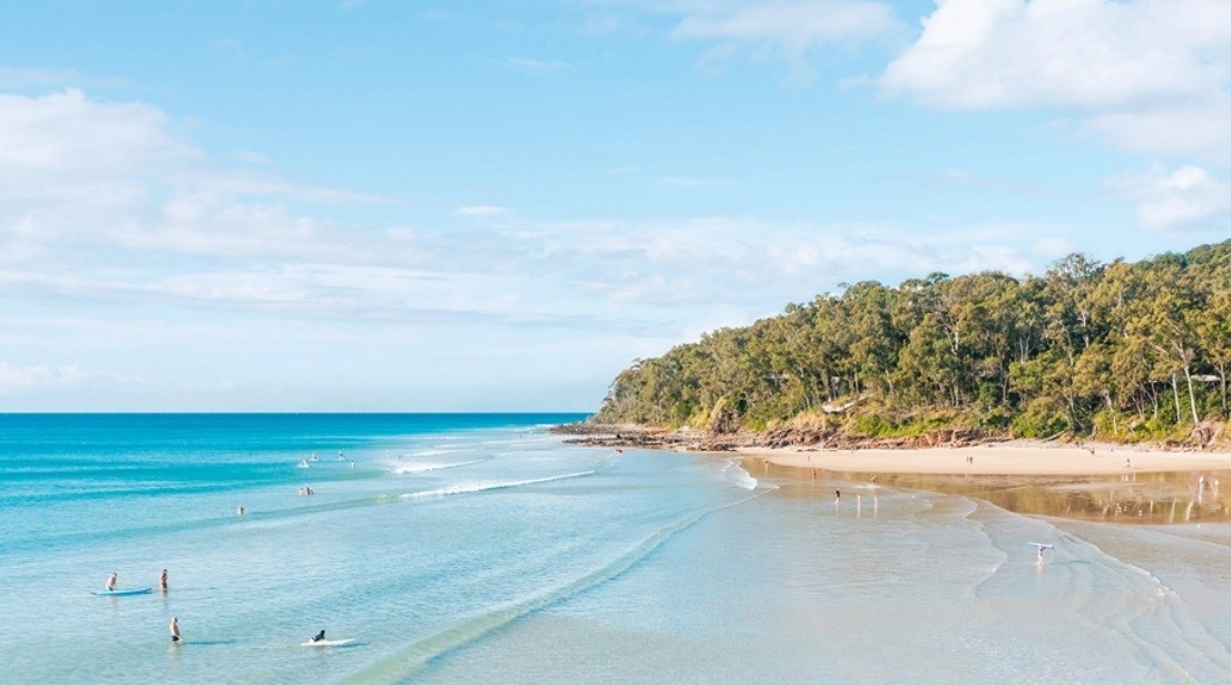 A white beach with turquoise water, with people swimming