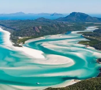 A landscape seen from air consisting of an island, a meandering lagoon, and white sands.