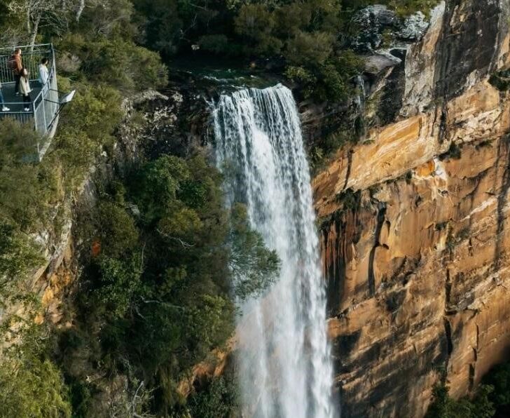 A waterfall and people watching it from a viewpoint