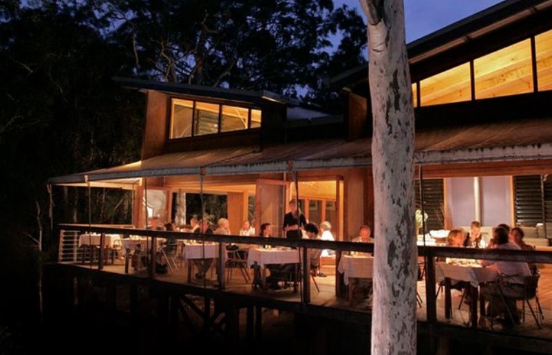 People dining in the evening on a gently light verandah under the trees