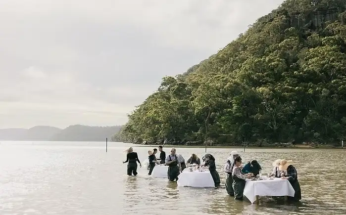 People eating oysters by tables in water