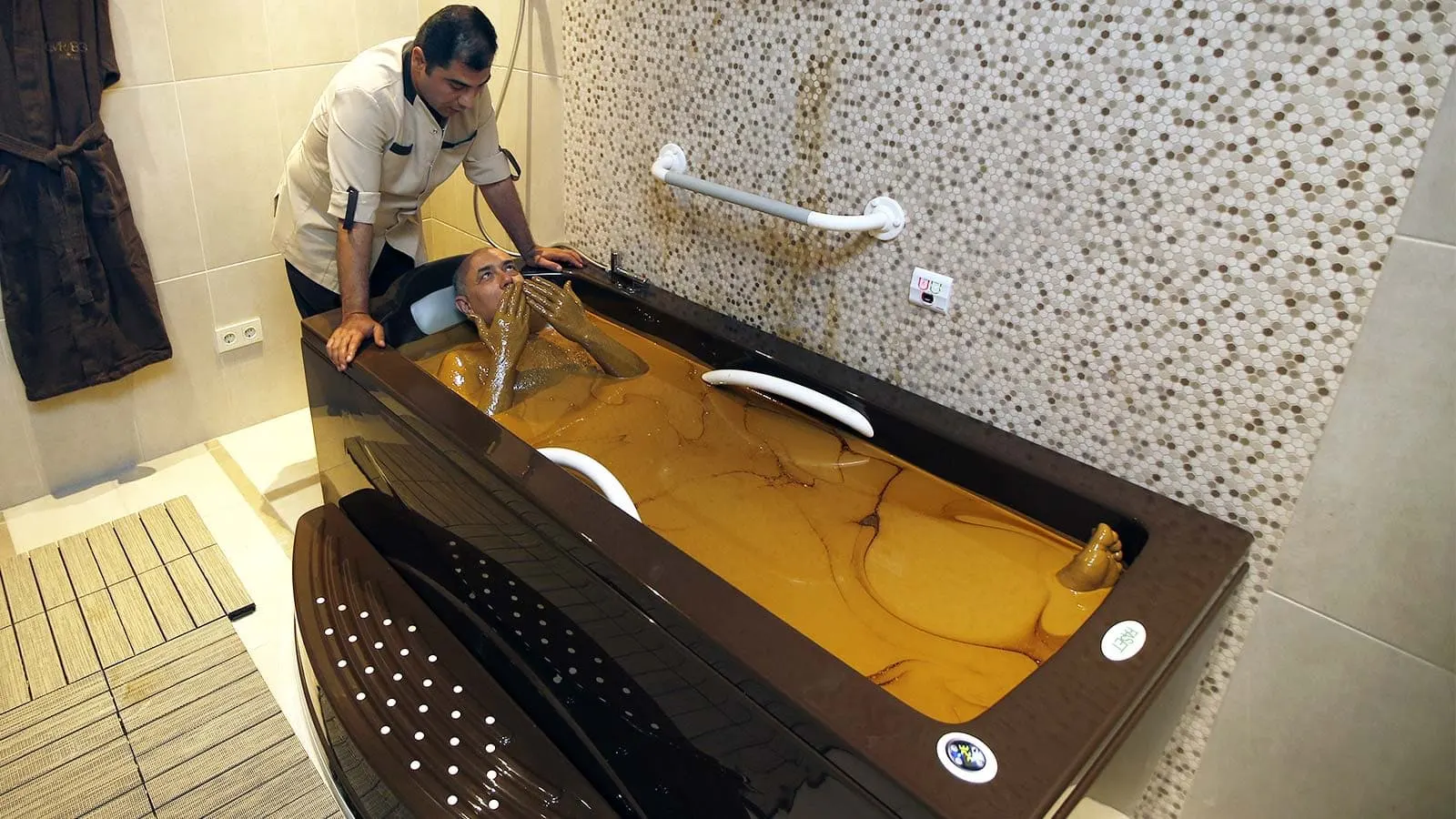 a doctor watches a woman in a bath of crude oil in naftalan azerbaijan