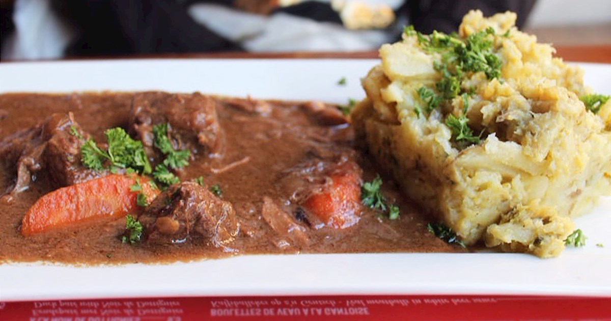 a white plate containing belgian beef stew carbonade flamande on a red placemat at nuetnigenough belgian restaurant in brussels
