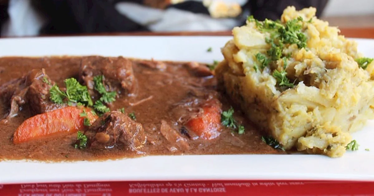 a white plate containing belgian beef stew carbonade flamande on a red placemat at nuetnigenough belgian restaurant in brussels