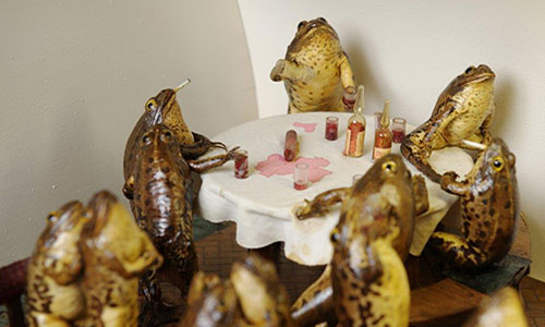 stuffed frogs sitting around a table with a white table cloth at froggyland museum in split croatia