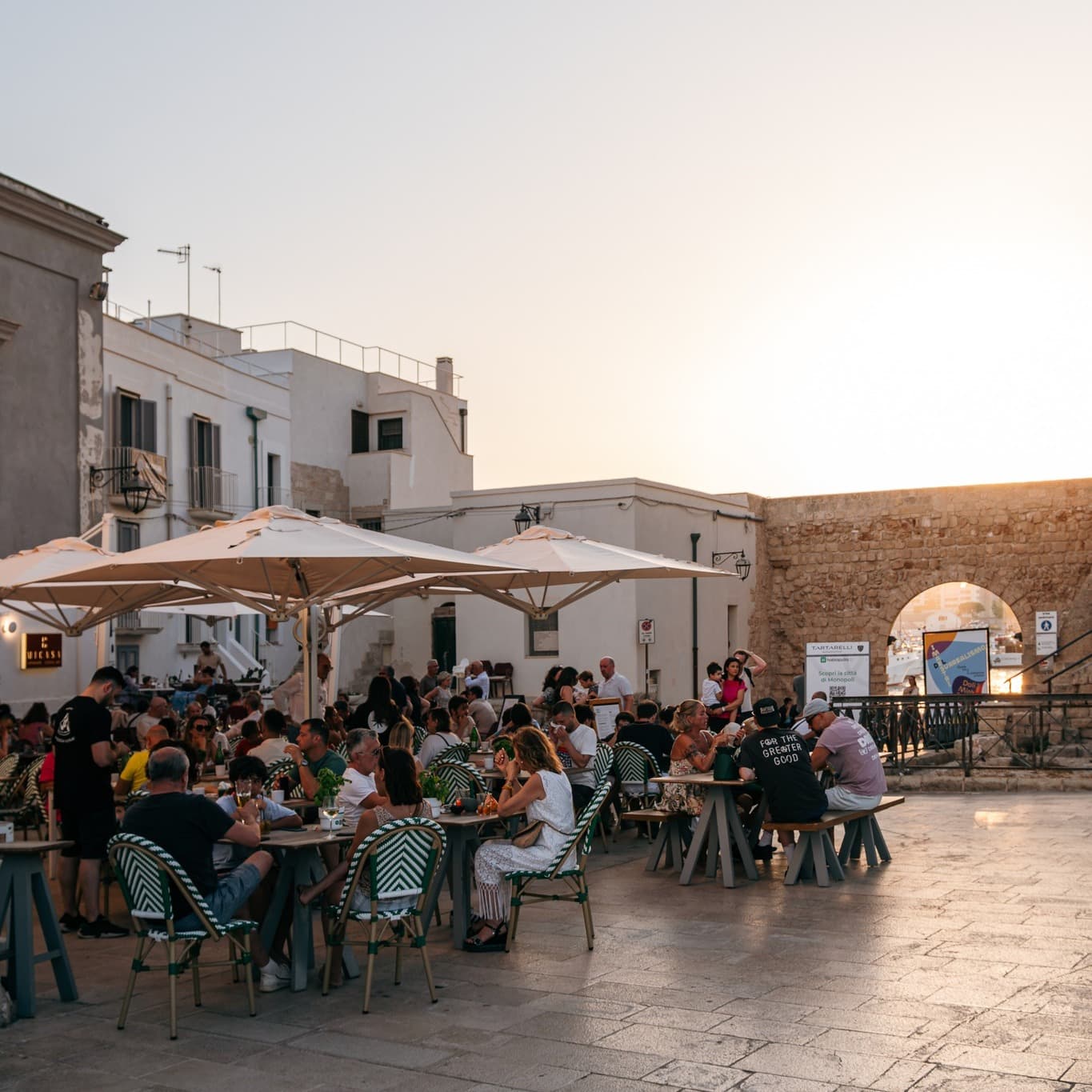tables and umbrellas outside tamborr italian pizzeria restaurant by the city walls of monopoli puglia italy